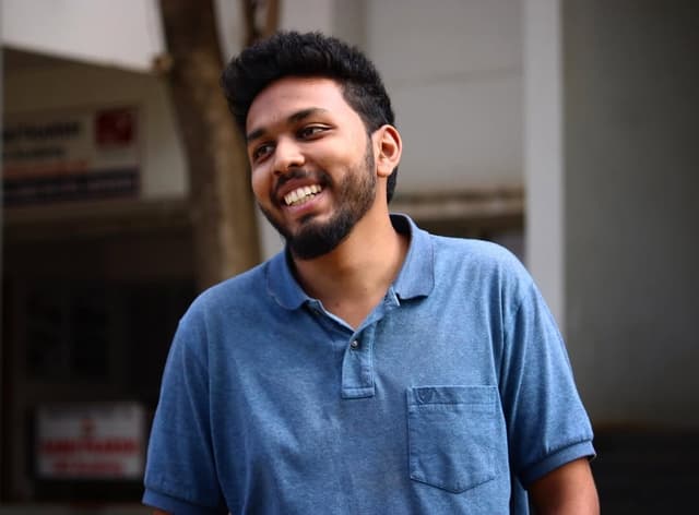 Nihad, outdoors in a blue polo shirt, smiling